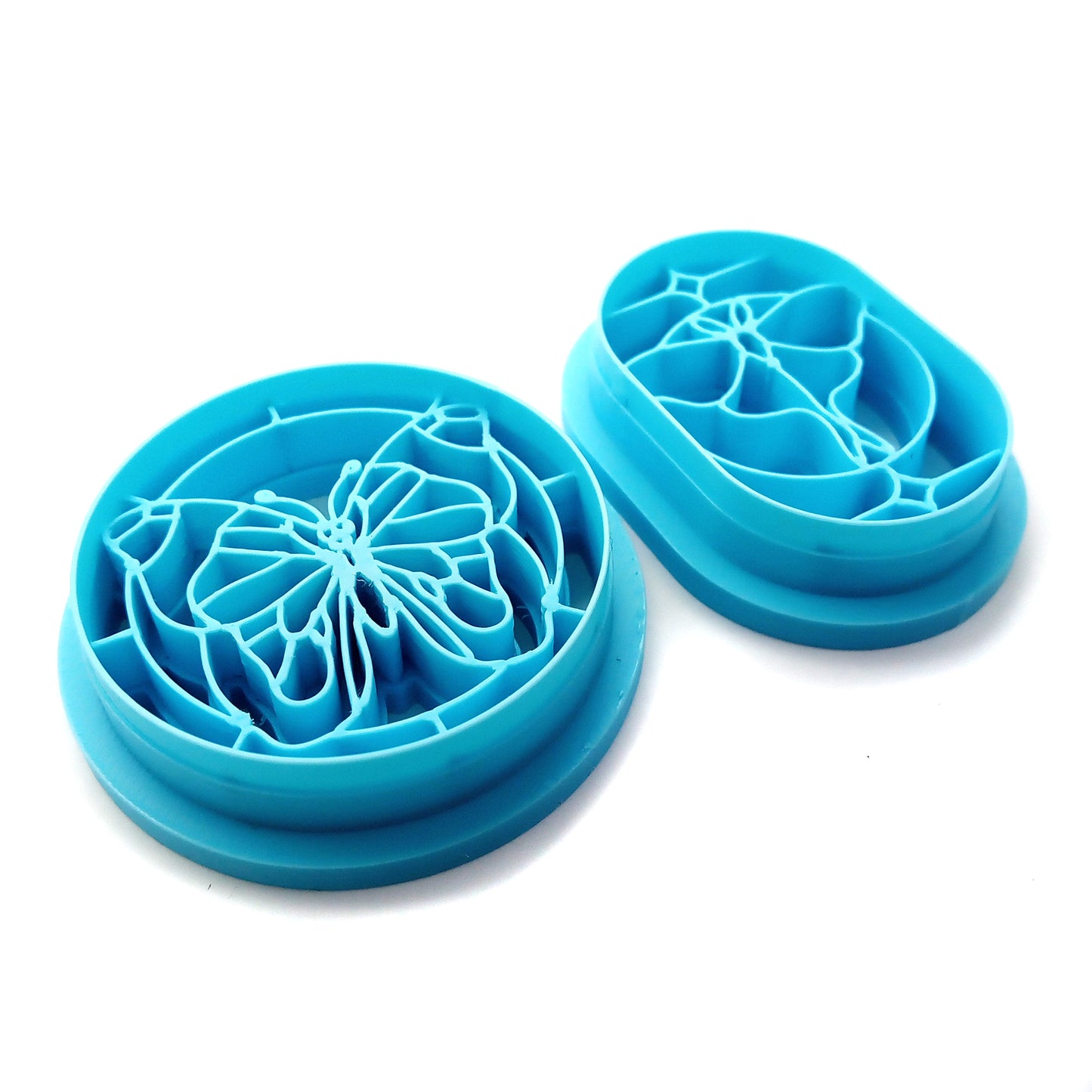 Two blue clay cutters on a white background, one butterfly and one moth in a stained-glass style border.