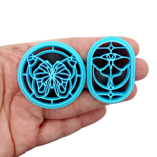 Two blue clay cutters in a hand, one butterfly and one moth in a stained-glass style border.