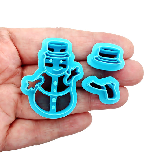 Set of blue snowman-themed clay cutters on a white background, held in a hand
