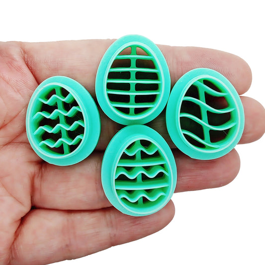Four green egg-shaped clay cutters with different patterns in a hand