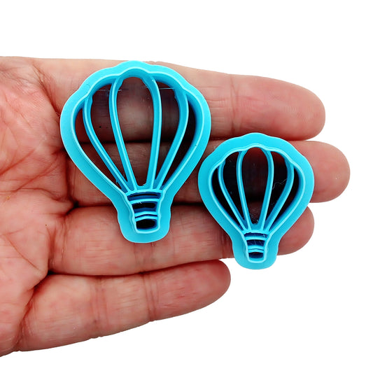 Two blue hot air balloon-shaped clay cutters held in a hand against a white background.