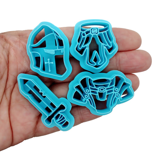 Set of blue clay cutters shaped like a helmet, sword, and armor in a hand