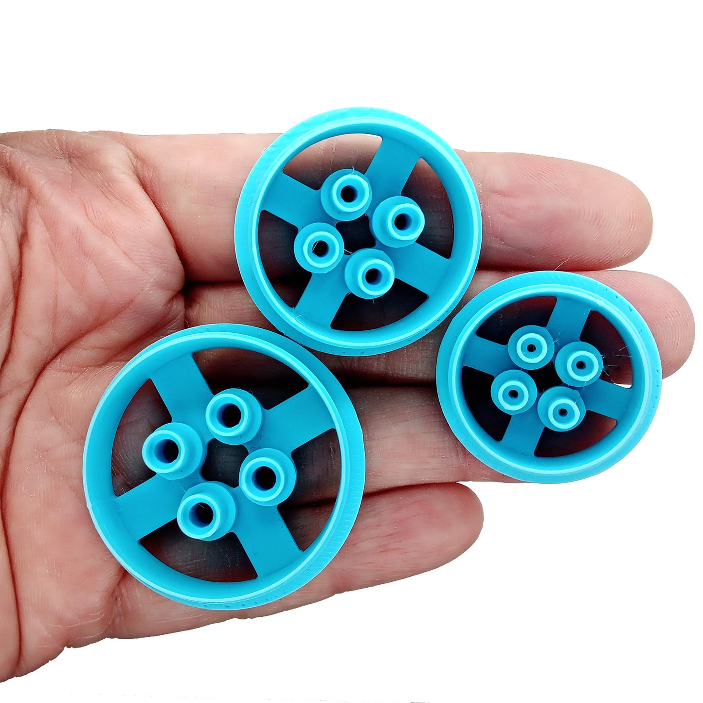 Three button clay cutters in different sizes held in a hand