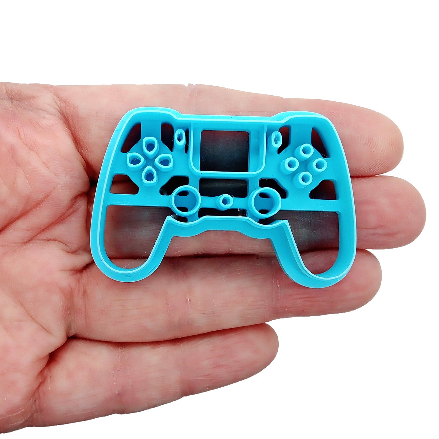 Blue clay cutter shaped like a gaming controller held in a hand on a white background
