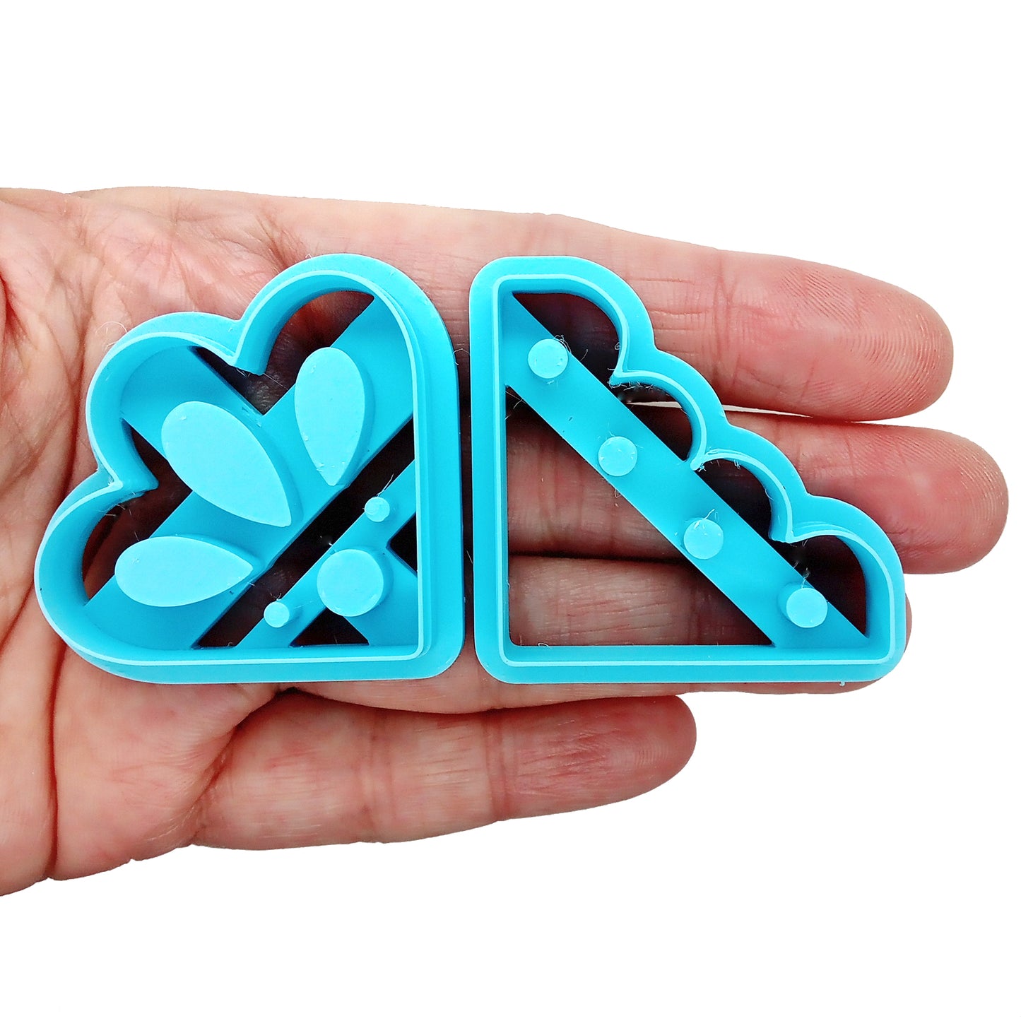 Blue clay cutters for decorative corners held in a hand on a white background