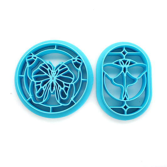Two blue clay cutters on a white background, one butterfly and one moth in a stained-glass style border.