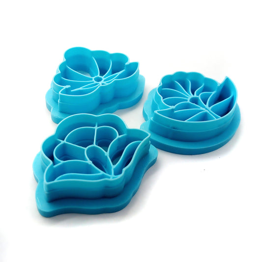 Three blue floral clay cutters against a white background