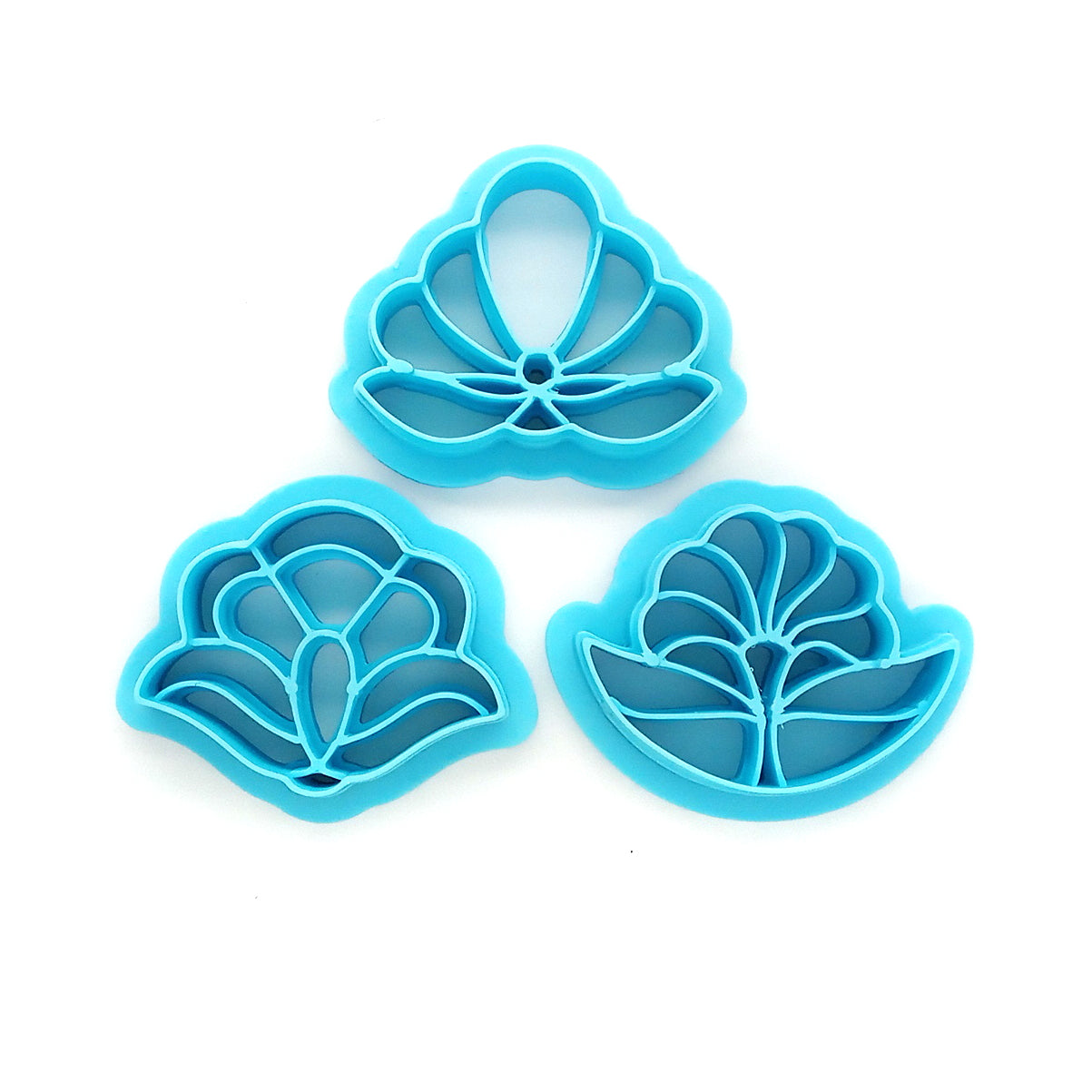 Three blue floral clay cutters against a white background