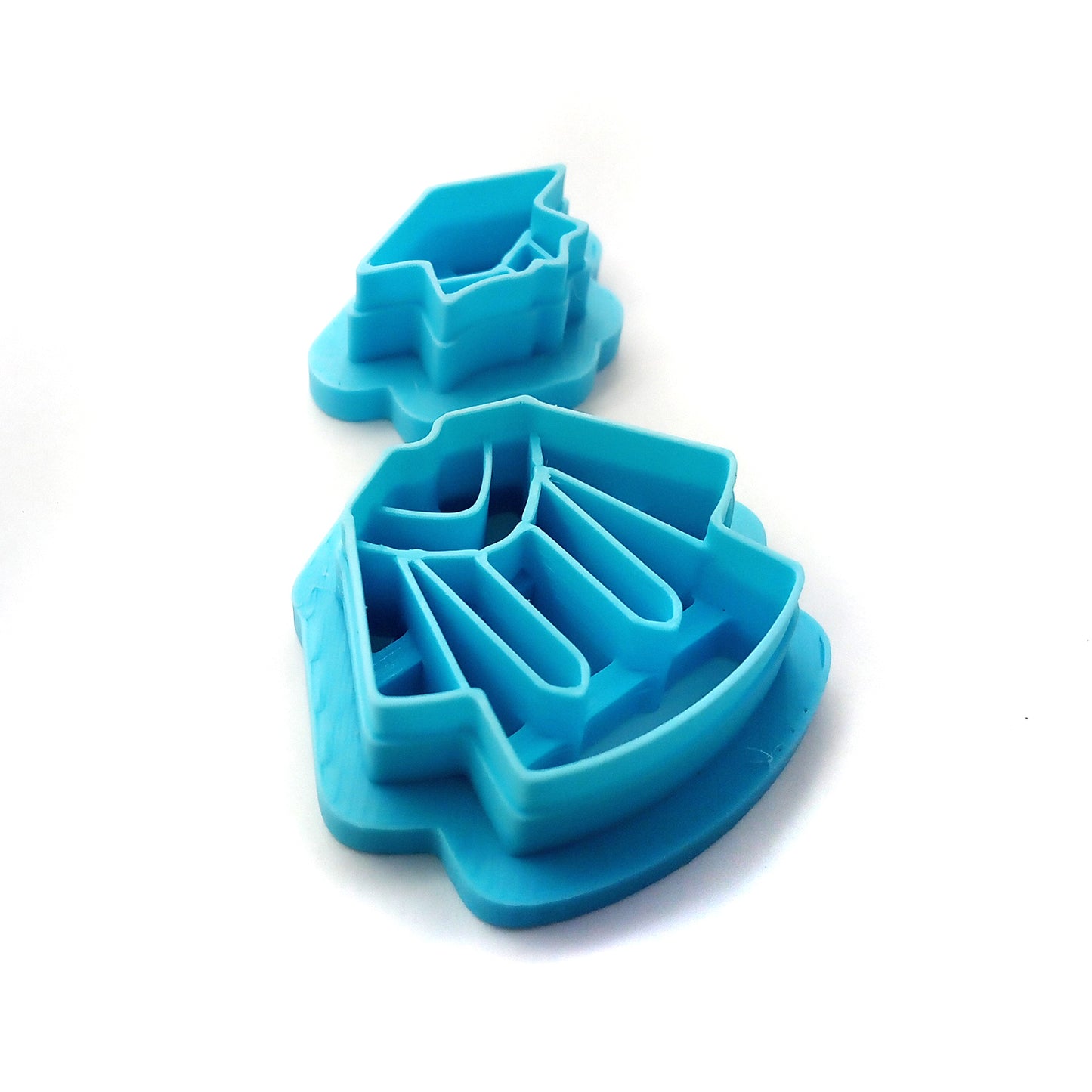 Two blue clay cutters shaped like graduation caps and gowns on a white background