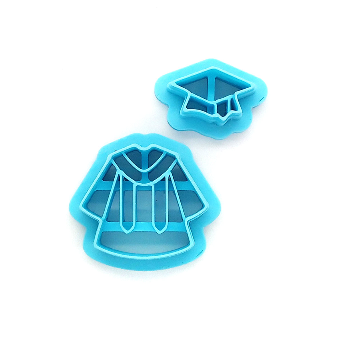 Two blue clay cutters shaped like graduation caps and gowns on a white background