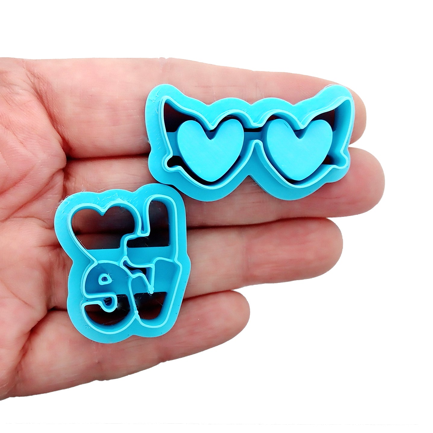 Blue clay cutters with the word "love" and heart-shaped sunglass lenses held in a hand