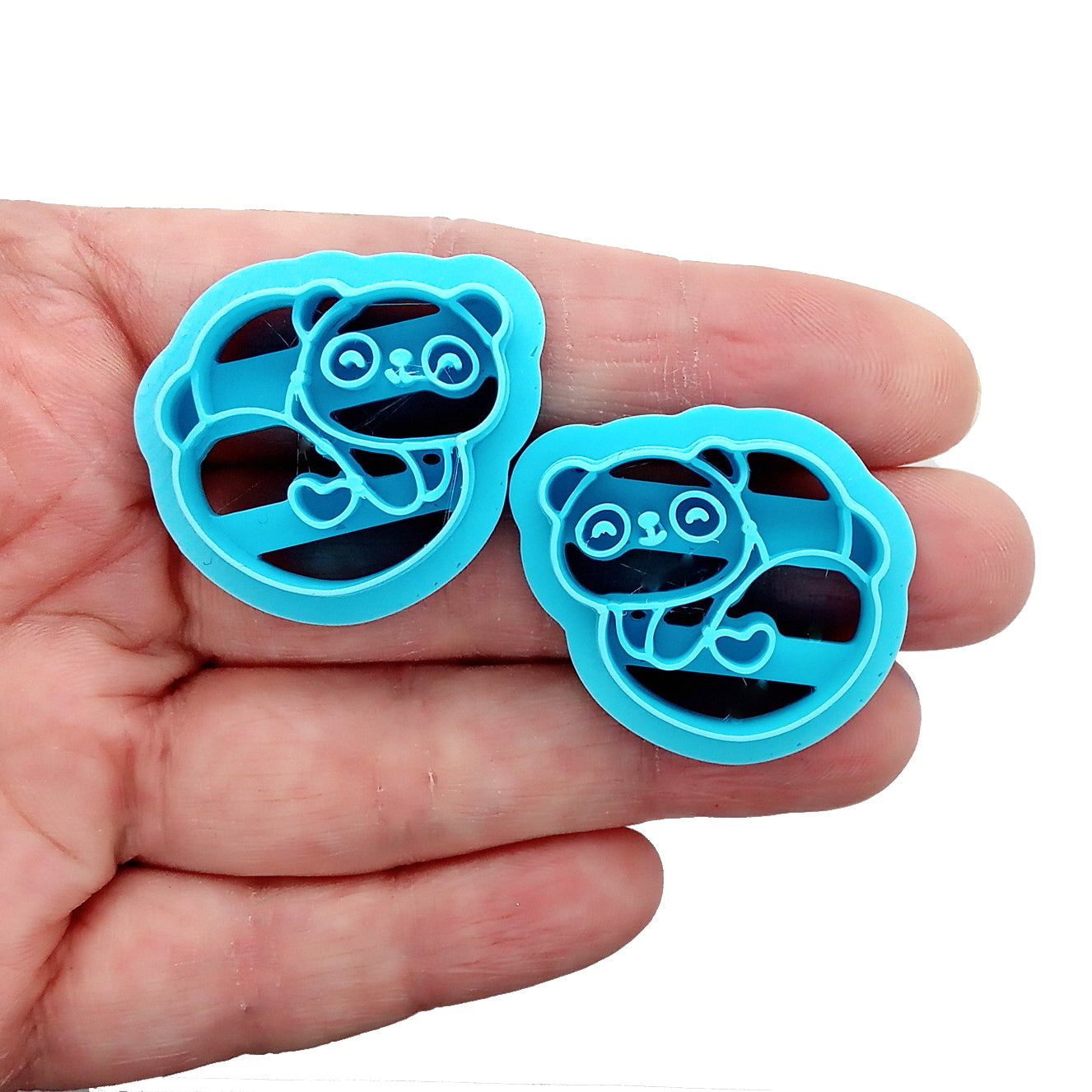 Two blue panda-shaped clay cutters held in a hand