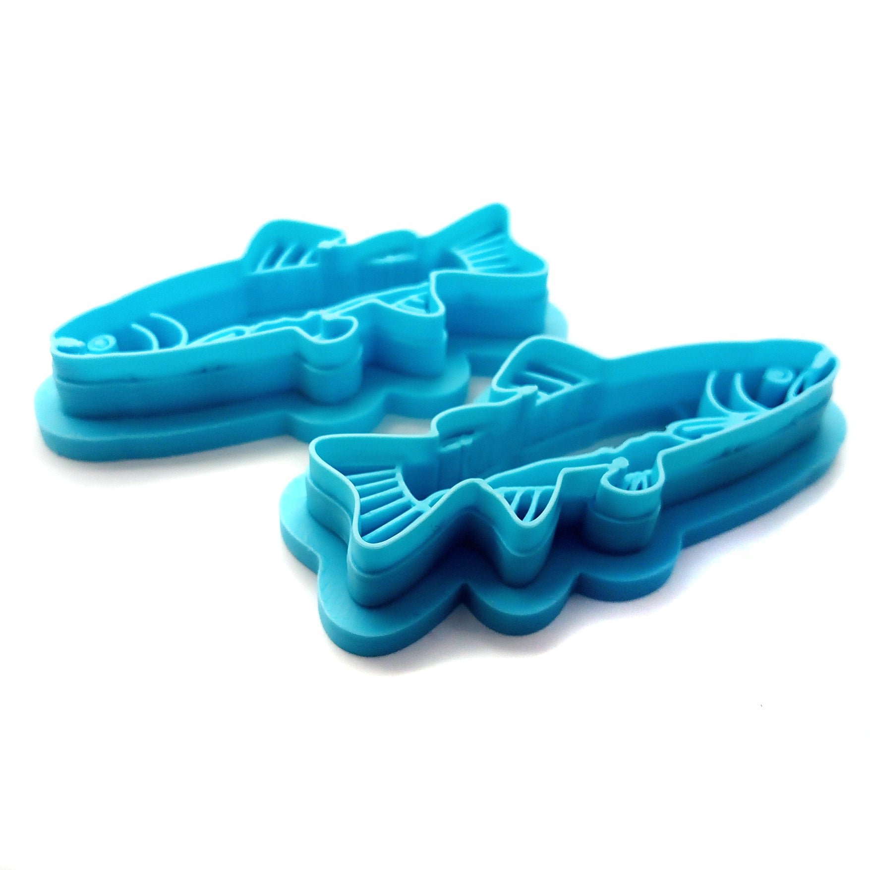 Two blue fish-shaped (salmon) clay cutters on a white background