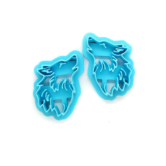 Two blue wolf-shaped clay cutters on a white background