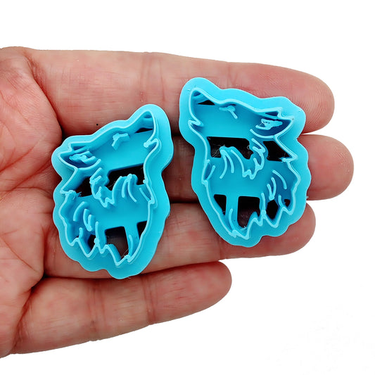 Two blue wolf-shaped clay cutters on a hand