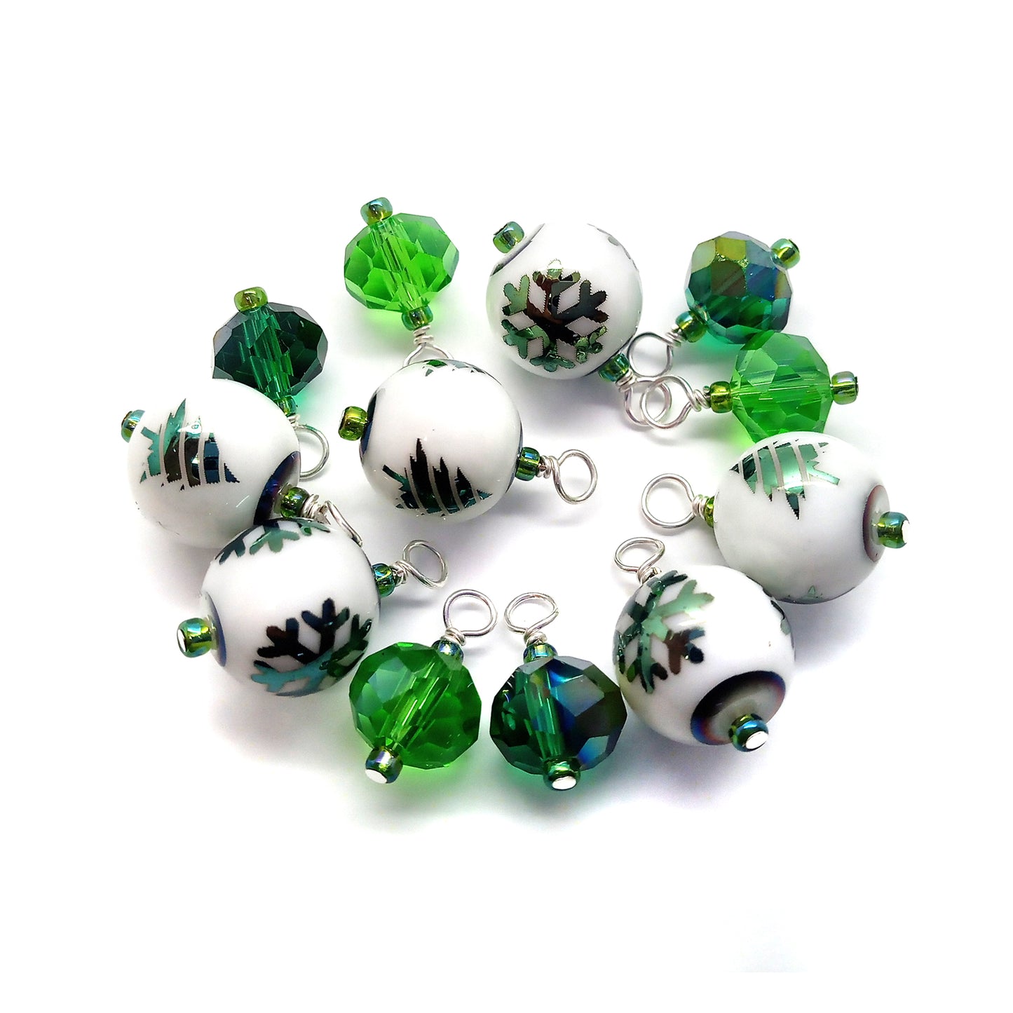 Set of green and white beaded charms on a white background, some with green Christmas trees or snowflakes.