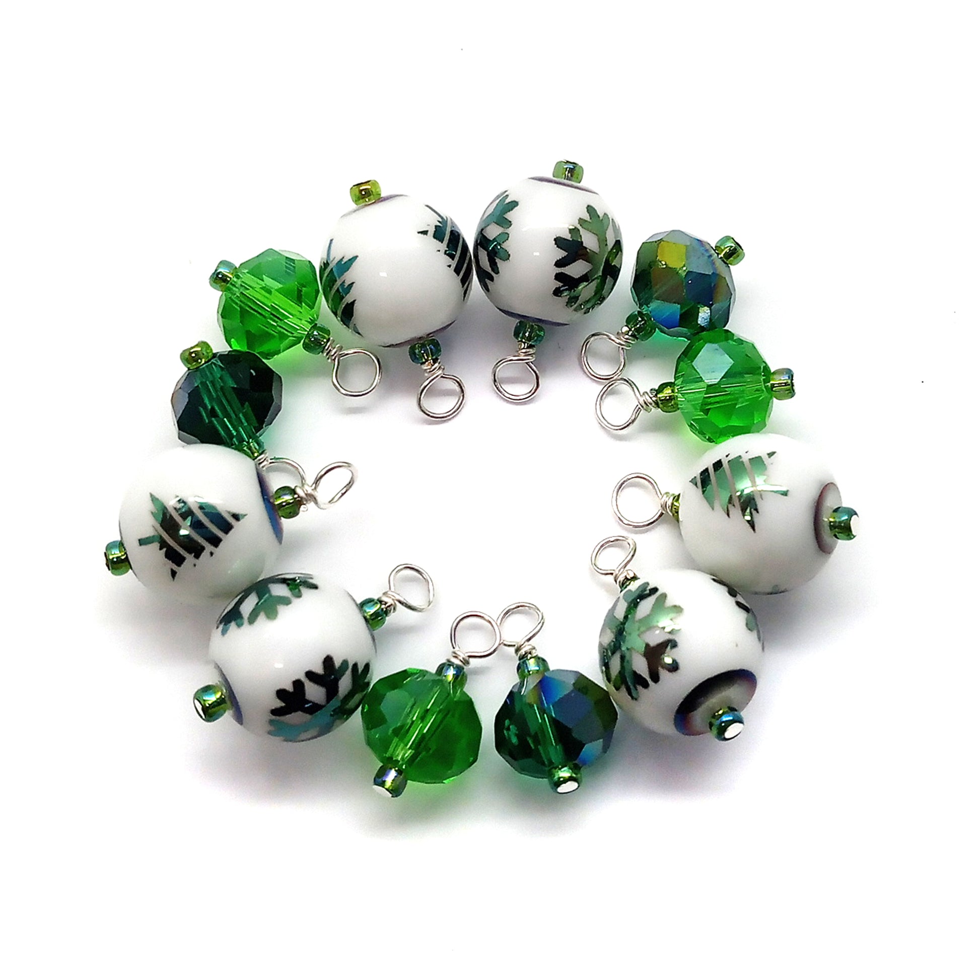 Set of green and white beaded charms on a white background, some with green Christmas trees or snowflakes.