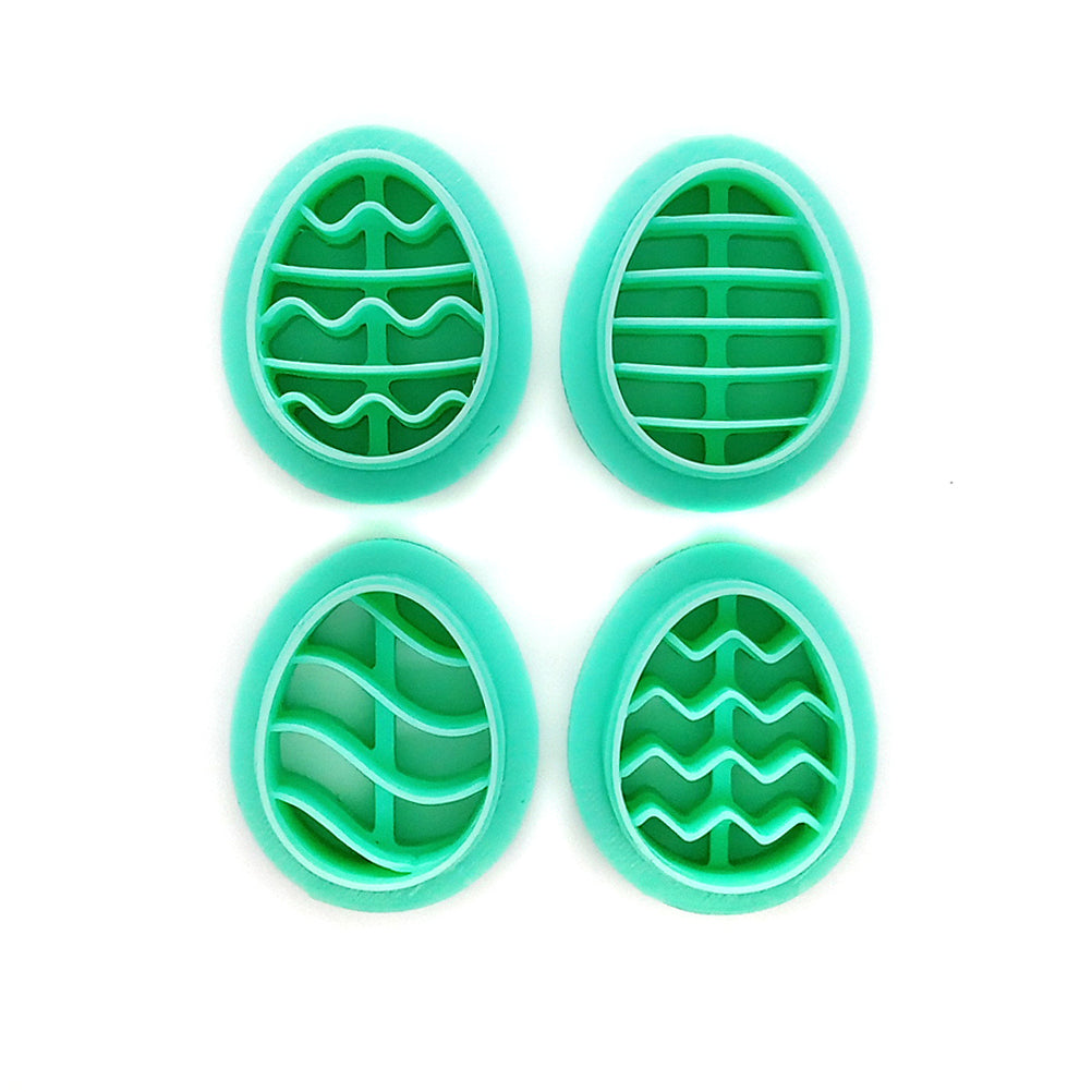 Four green egg-shaped clay cutters with different patterns on a white background