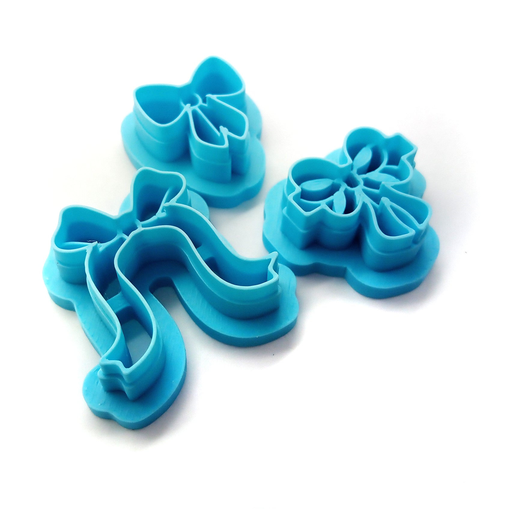 Three blue bow-shaped clay cutters against a white background