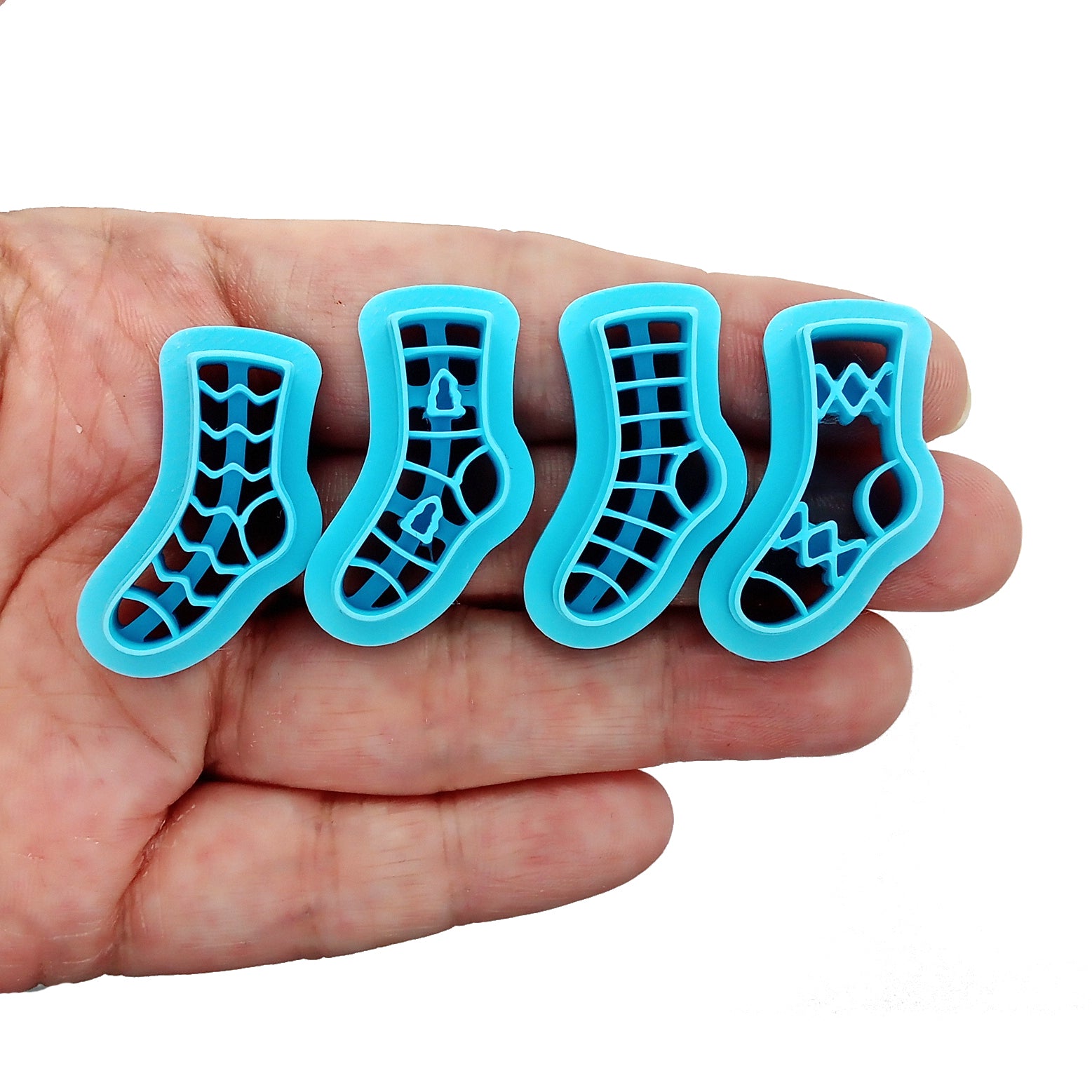 Set of 4 stocking or sock clay cutters in various patterns, held in hand.