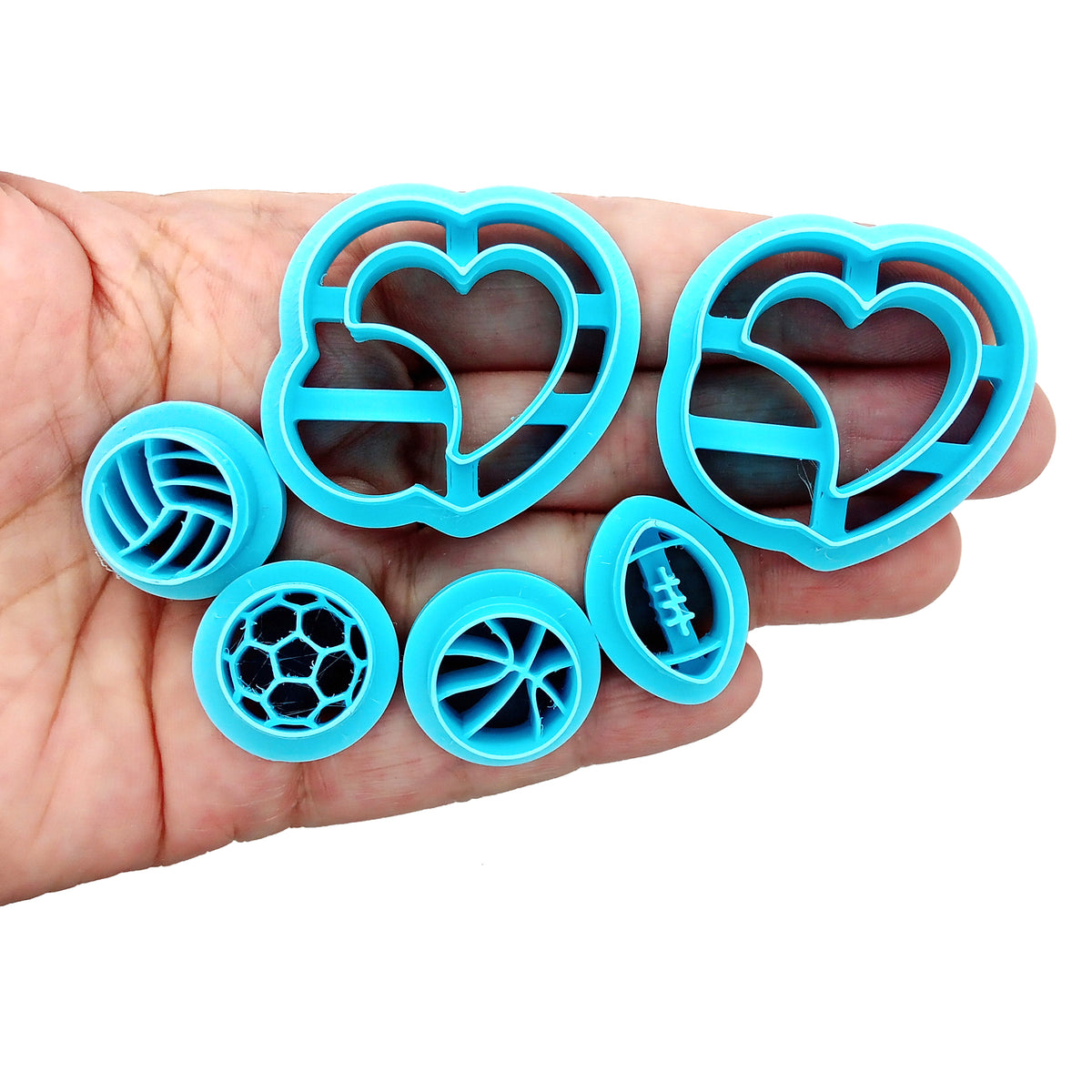 Set of clay cutters with large hearts holding sports balls