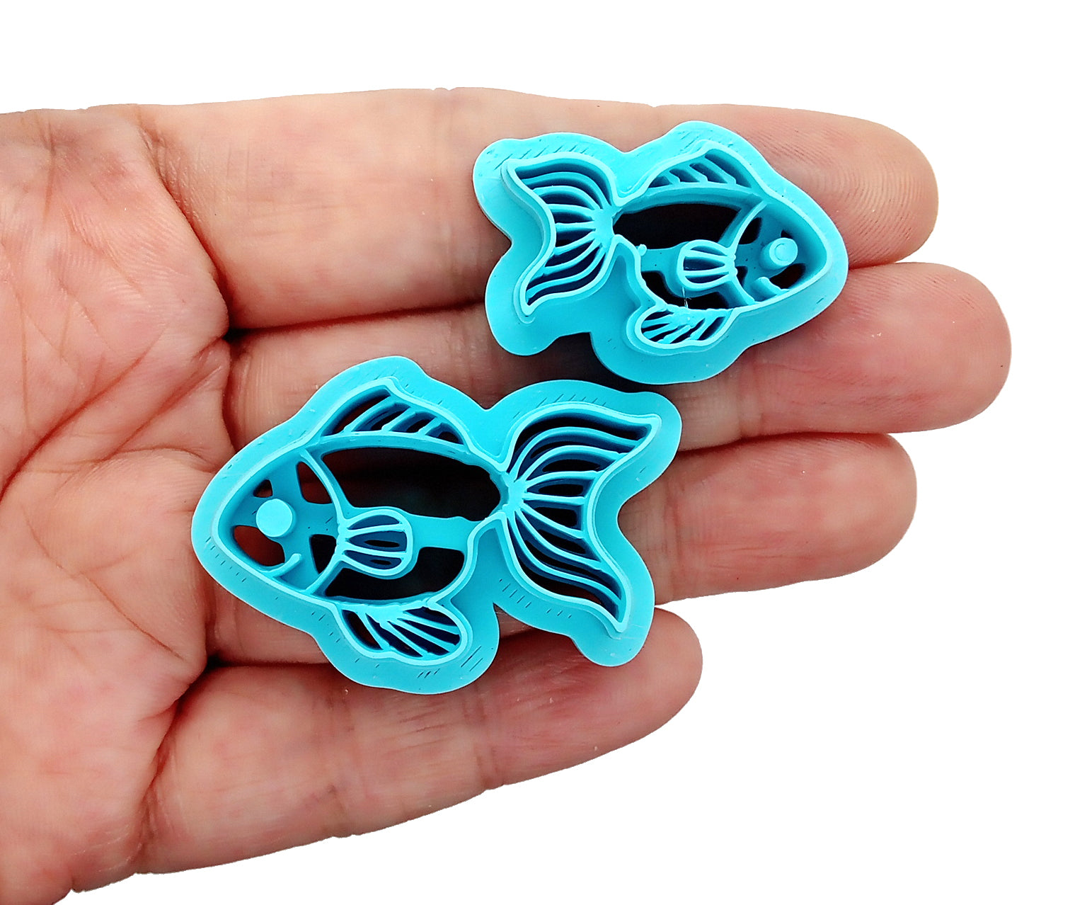 Two goldfish clay cutters, held in hand.