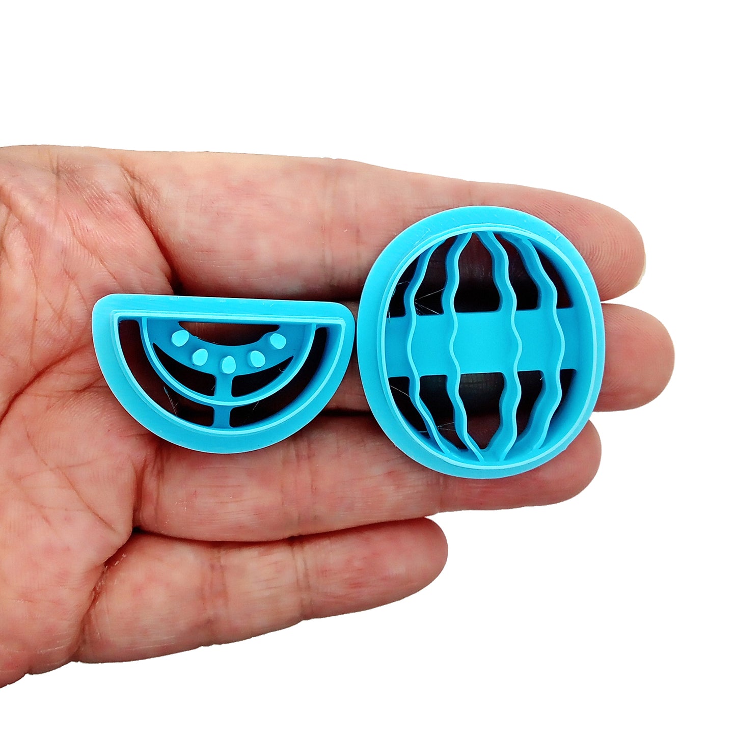 Set of blue clay cutters shaped like watermelons held in a hand