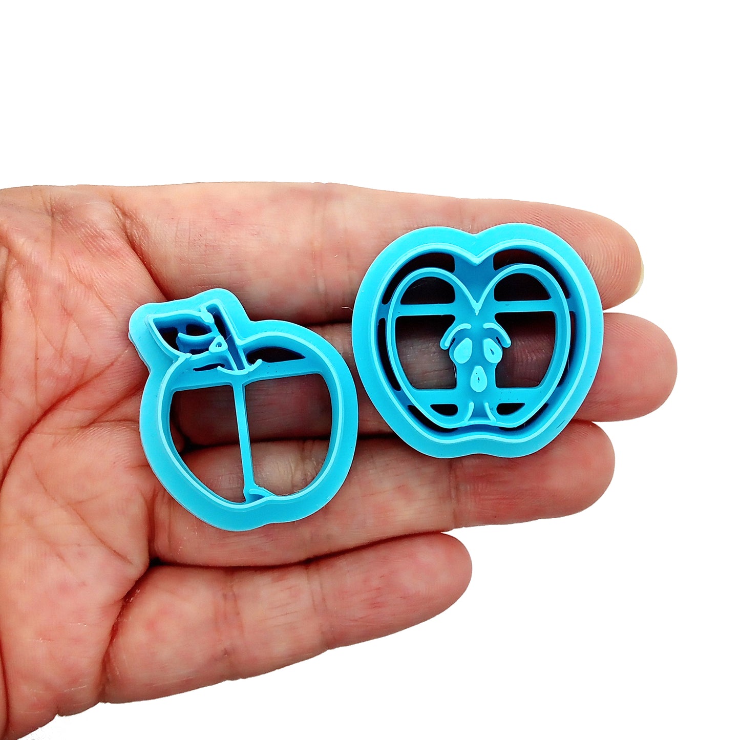 Set of blue clay cutters shaped like  apples held in hand