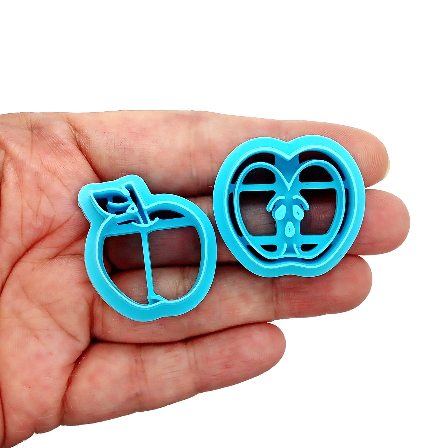 Set of blue clay cutters shaped like  apples held in hand
