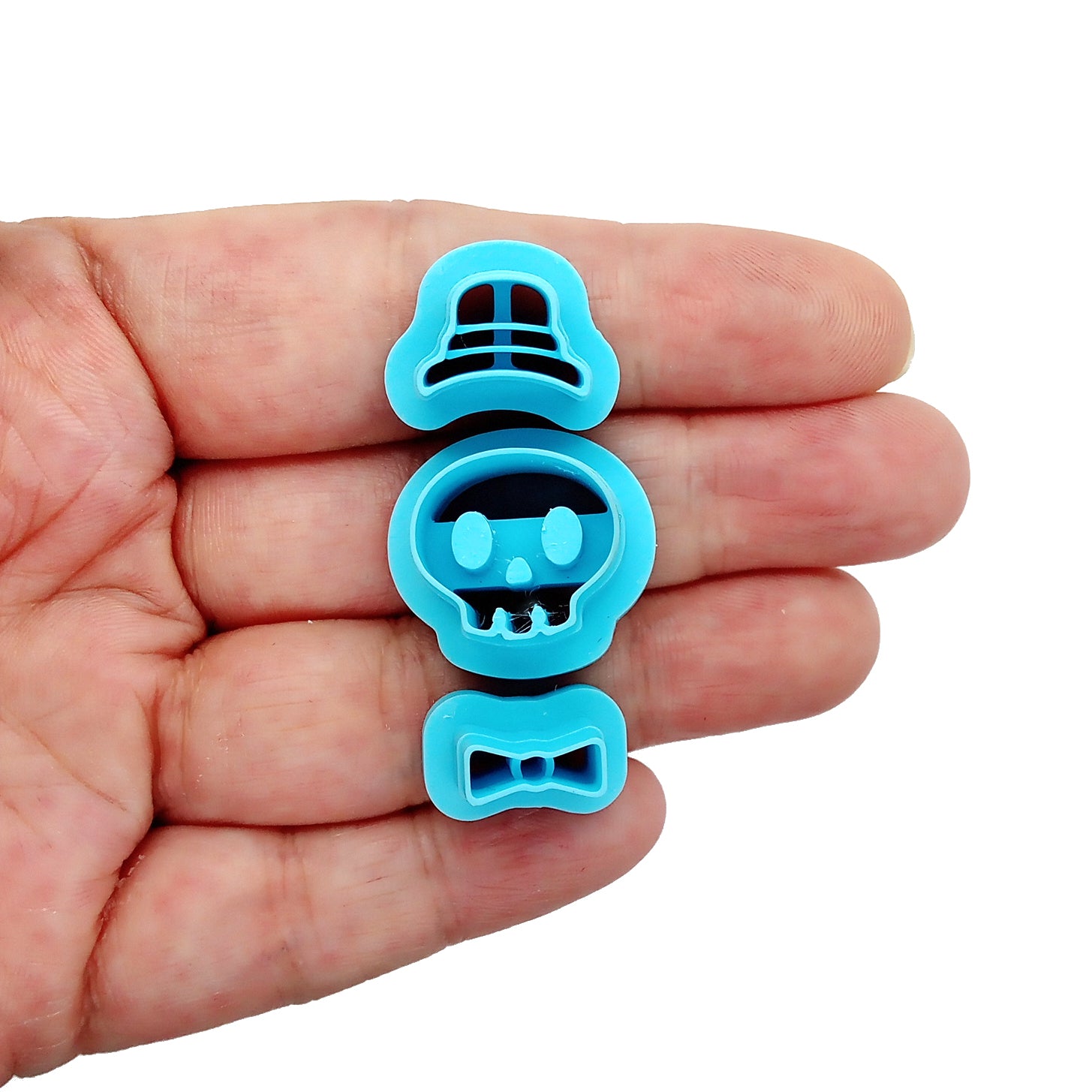 Blue Skull clay cutter with top hat and bow tie, held in hand.
