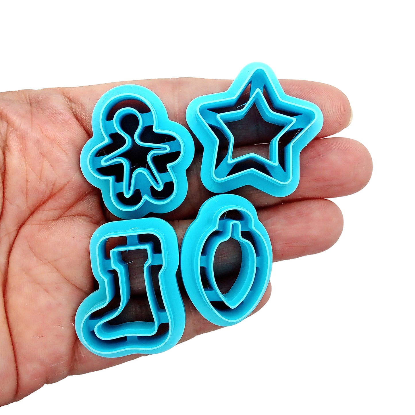 Set of blue Christmas or winter-themed clay cutters held in hand.