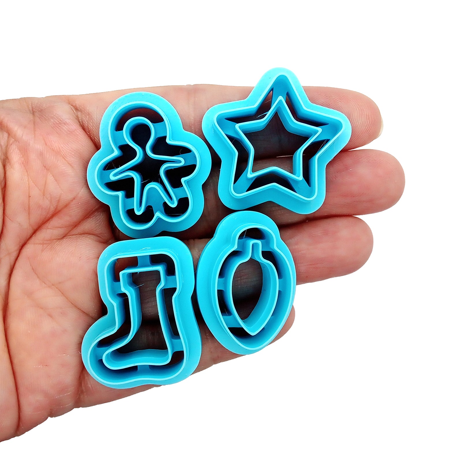 Set of blue Christmas or winter-themed clay cutters held in hand.