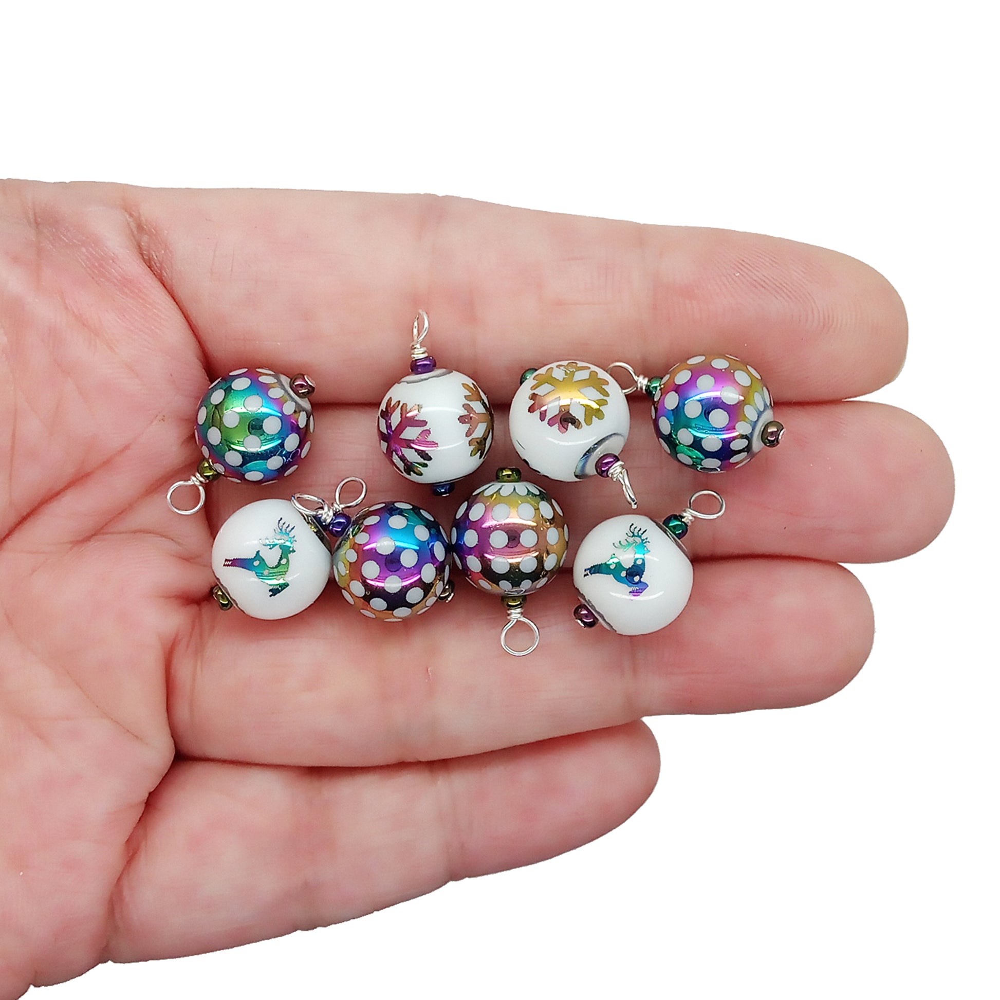 Miniature glass bauble ornaments with rainbow polka dots, snowflakes and reindeer, held in hand.