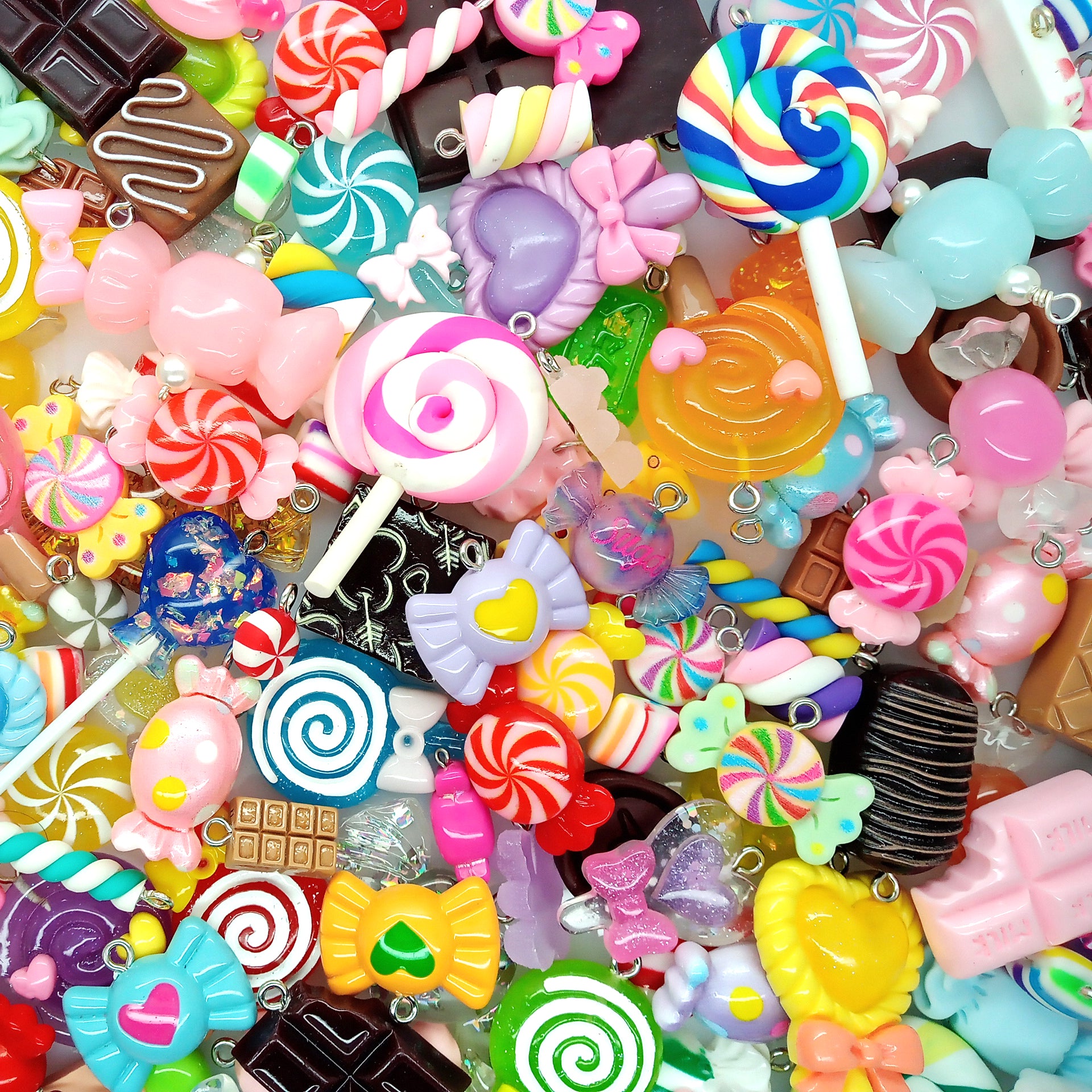 Assorted colorful candy-shaped charms made from resin cabochons, polymer clay and beads.